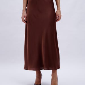 May include: A brown satin midi skirt with a slight A-line shape.