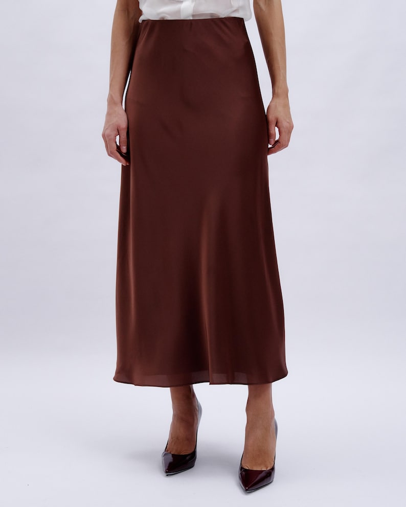 May include: A brown satin midi skirt with a slight A-line shape.
