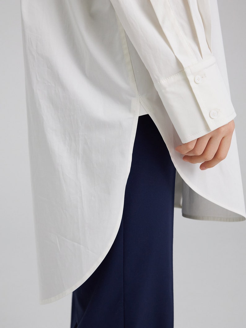 Pu&ograve; includere: Una camicia bianca a maniche lunghe con un orlo arrotondato e un polsino abbottonato. La camicia &egrave; realizzata in un tessuto leggero e ha una vestibilit&agrave; rilassata.