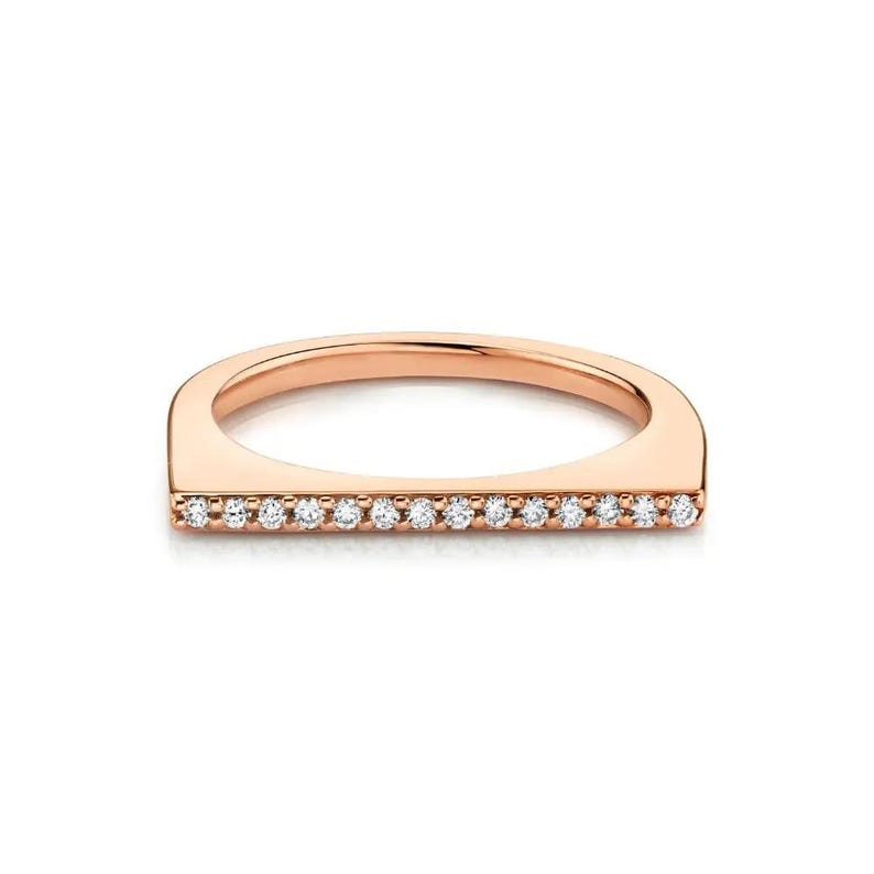Puede incluir: Un anillo de oro rosa con un dise&ntilde;o de barra horizontal plana en la parte superior. La barra est&aacute; engastada con una fila de catorce peque&ntilde;as piedras redondas, claras y de talla brillante que abarcan el ancho de la banda del anillo.