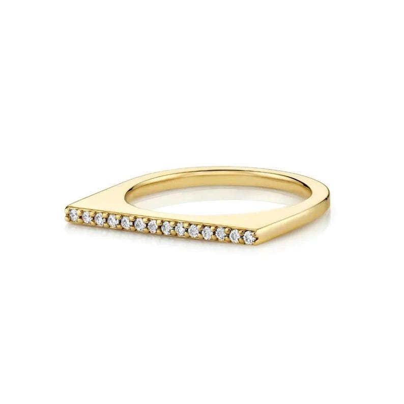 Puede incluir: Un anillo de oro con un dise&ntilde;o de barra horizontal plana en la parte superior. La barra est&aacute; engastada con una hilera de peque&ntilde;as piedras claras de corte redondo que abarcan el ancho de la banda. El metal tiene un acabado pulido y brillante.