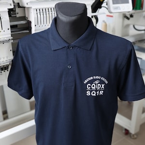 May include: A navy blue polo shirt with a white embroidered logo that says "Amateur Radio Station CQIDX SQ1R".