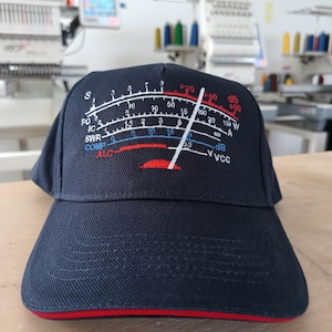 Könnte beinhalten: Marineblaue Baseballkappe mit rotem Rand, bestickt mit einem Messgerätdesign in Weiß, Rot und Blau. Die Kappe zeigt die Schriftzüge "SWR", "ALC", "dB" und "VCC".