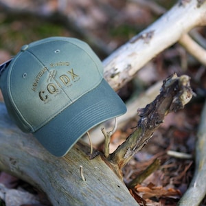 Peut inclure: Une casquette de baseball verte avec le texte "Amateur Radio CQDX" brodé en or sur le devant.