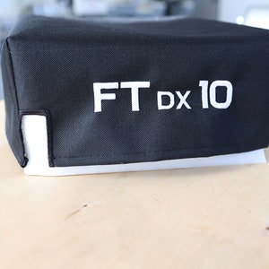 Pode incluir: Capa de tecido preto com texto branco que diz "FT DX 10".