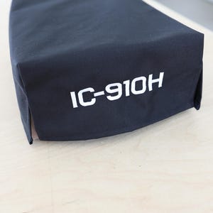 Pode incluir: Capa de tecido preto com bordado branco que diz "IC-910H".