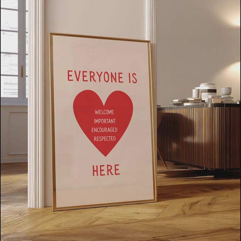 Może przedstawiać: Oprawiony plakat ze słowami "EVERYONE IS HERE" w kolorze czerwonym, z czerwonym sercem pośrodku. Wewnątrz serca znajdują się słowa "WELCOME, IMPORTANT, ENCOURAGED, RESPECTED". Rama jest złota.