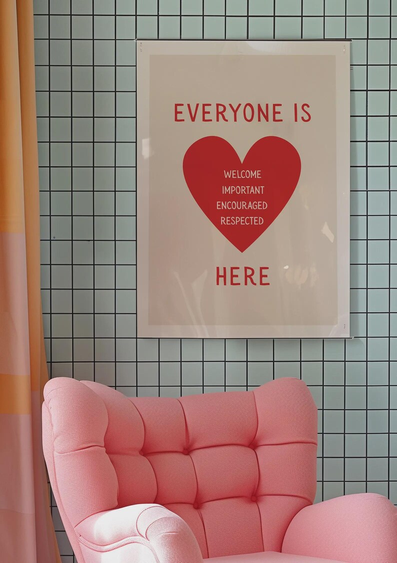 Może przedstawiać: Oprawiony plakat ze słowami "EVERYONE IS HERE" na czerwono, z czerwoną grafiką serca zawierającą słowa "WELCOME, IMPORTANT, ENCOURAGED, RESPECTED". Plakat wisi na jasnoniebieskiej kafelkowej ścianie. R&oacute;żowy fotel znajduje się na pierwszym planie.