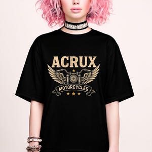 May include: A black short-sleeve t-shirt featuring a gold graphic print on the chest. The design displays the text ACRUX above a stylized motorcycle handlebar with wings, the word MOTORCYCLES on a banner, and three small stars below the banner.