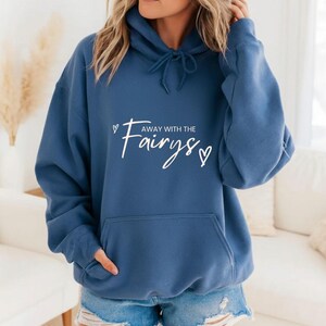May include: A blue hoodie with a front pocket and a drawstring. The white text "Away with the Fairys" is centered on the front, with a heart symbol on each side of the word "Fairys".