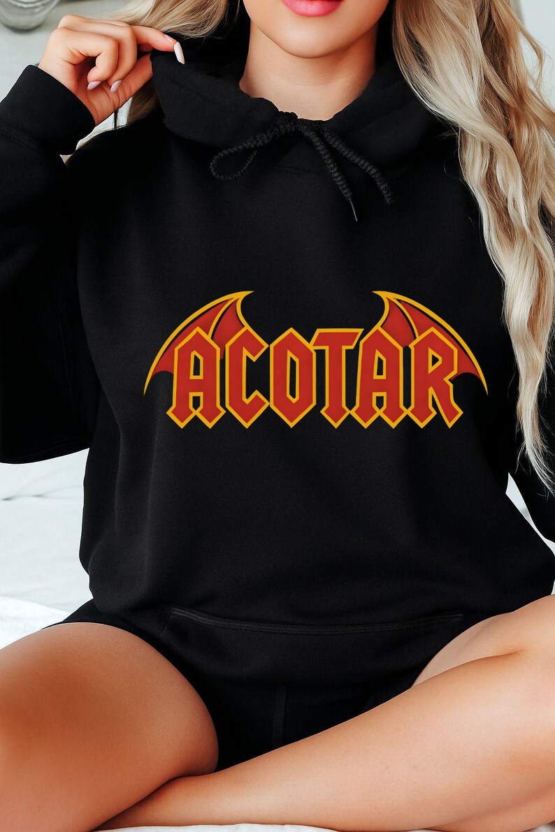 May include: Black hoodie with the word "ACOTAR" in red and yellow lettering. The design features a stylized font with wing-like accents above the text. The hoodie has a drawstring hood and long sleeves.