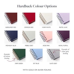 May include: A selection of hardback notebooks in various colors, including burgundy red, crimson red, ivory white, and pastel lilac. Each notebook features a spiral binding and is available with gold or silver foiling.