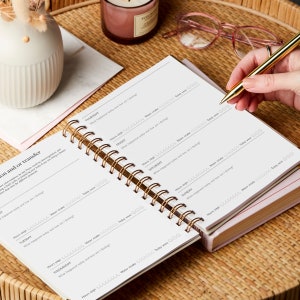 The IVF book is laid flat open to show a double page spread of the embryo transfer or an alternative protocol.A hand is poised to write in the IVF planner. The IVF journal is placed on a coffee table with a pair of glasses and a candle.