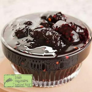 May include: A glass bowl filled with a dark, rich, homemade blackberry jam. The jam is thick and glossy, with visible blackberry pieces. The bowl is clear and has a textured surface. The image includes the text "take organics naturel food".