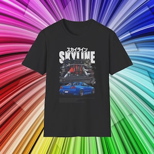 May include: Black t-shirt featuring a blue sports car illustration with the word "SKYLINE" in white, and Japanese characters above. The graphic also includes an engine diagram. The shirt is made of a soft material.