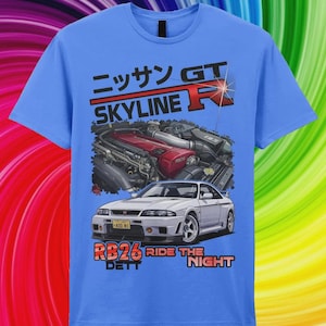 May include: A light blue t-shirt featuring a graphic print of a white Nissan Skyline GT-R car and an RB26 engine. The text reads "ニッサン GT SKYLINE R" and "RB26 DETT RIDE THE NIGHT". The design includes a red engine cover and a yellow license plate.