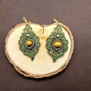 May include: A pair of green and brown knotted earrings with a tiger's eye stone in the center of each earring.