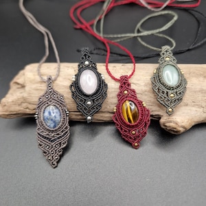 Puede incluir: Cuatro collares de macramé con piedras de diferentes colores. Los collares están hechos con un cordón gris oscuro, rojo, verde y negro. Las piedras son de color rosa claro, azul claro, verde y marrón.
