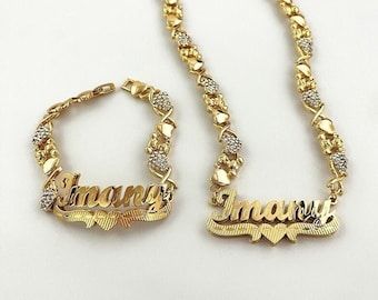 Può includere: Set di collana e braccialetto in oro con il nome "Imari" scritto in corsivo. La catena è composta da cuori intrecciati con piccole pietre trasparenti.