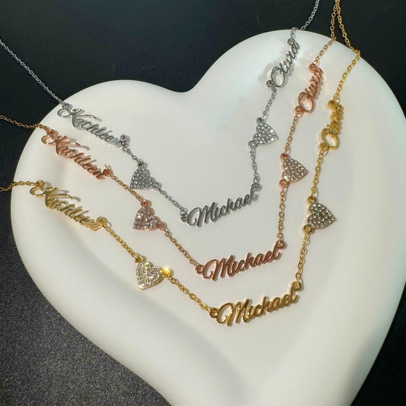 May include: Three gold necklaces with heart charms and nameplates. The names on the necklaces are "Michael", "Olivia", and "Kathleen".