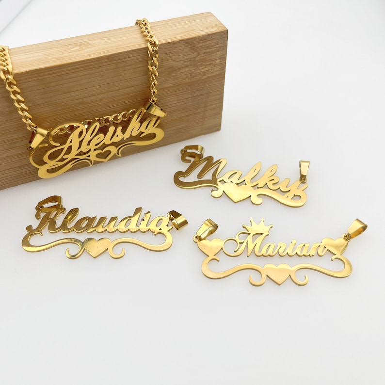 May include: Four gold-tone necklaces with personalized names, each with a heart charm. The names are "Alesha", "Malky", "Klaudia", and "Mariano".
