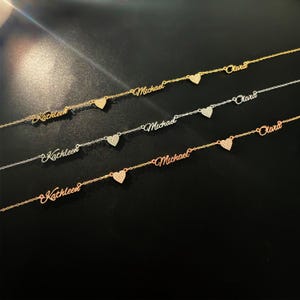 May include: Four delicate gold, silver, and rose gold necklaces with heart charms and personalised names, including "Kathleen", "Michael", and "Olivia".