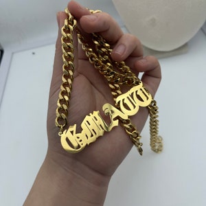Peut inclure: Collier en chaîne dorée avec un pendentif personnalisé en forme de plaque. La plaque est en police gothique et porte l'inscription "KARLAWU".