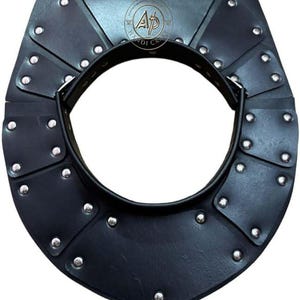 Può includere: Armatura per il collo in pelle nera con rivetti color argento. L'armatura ha un design a strati con un'apertura circolare per il collo. Il prodotto ha un tema medievale o fantasy.