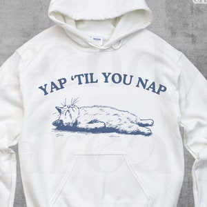 May include: White hoodie with a blue illustration of a cat napping and the text "YAP 'TIL YOU NAP" printed on the front.