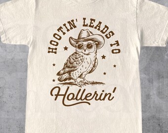 Peut inclure: Un t-shirt beige avec une illustration brune d'un hibou portant un chapeau de cowboy et des lunettes de soleil. Le texte "Hootin' Leads to Hollerin'" est imprimé sur le t-shirt.
