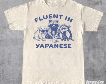 May include: A white t-shirt with a blue graphic of animals wearing sunglasses and the text "Fluent in Japanese".