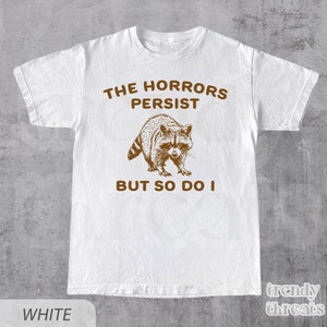 The Horrors Persist But So Do I Shirt • Sarcastic Shirt • Funny Mental Health Tee • Meme Shirt • Raccoon Gift • Funny Gift For Him & Her
