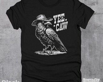 Peut inclure: T-shirt noir avec un graphique d'un corbeau portant un chapeau de cowboy. Le texte "Yee Caw" est imprimé sur le t-shirt.