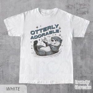 May include: White t-shirt with a graphic of an otter holding a fish and the text "Otterly Adorable".