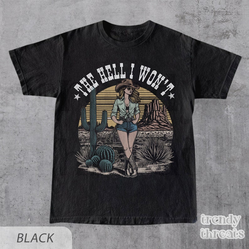 May include: Black t-shirt with a vintage-style graphic of a woman in a cowboy hat standing in a desert landscape. The text "THE HELL I WON'T" is written in a circle around the woman.