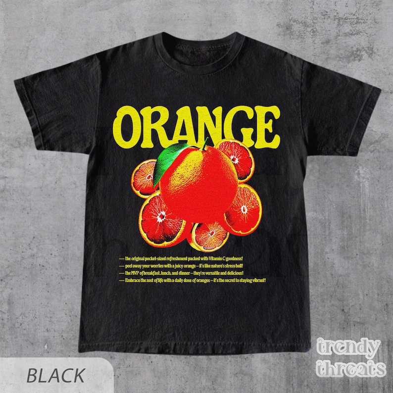 May include: Black t-shirt with a graphic design of a stylized orange with the word "ORANGE" in yellow letters. The text below the orange reads: "the original pocket-sized refreshment packed with Vitamin C goodness! peel away your worries with a juicy orange - it's like nature's stress ball! the MVP of breakfast, lunch, and dinner - they're versatile and delicious! Embrace the zest of life with a daily dose of oranges - it's the secret to staying vibrant!"