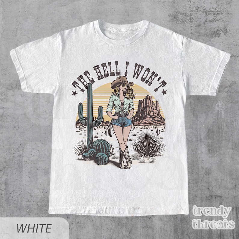 May include: White t-shirt with a graphic of a woman in a cowboy hat and denim shorts standing in a desert landscape with a cactus and the text "The Hell I Won't".