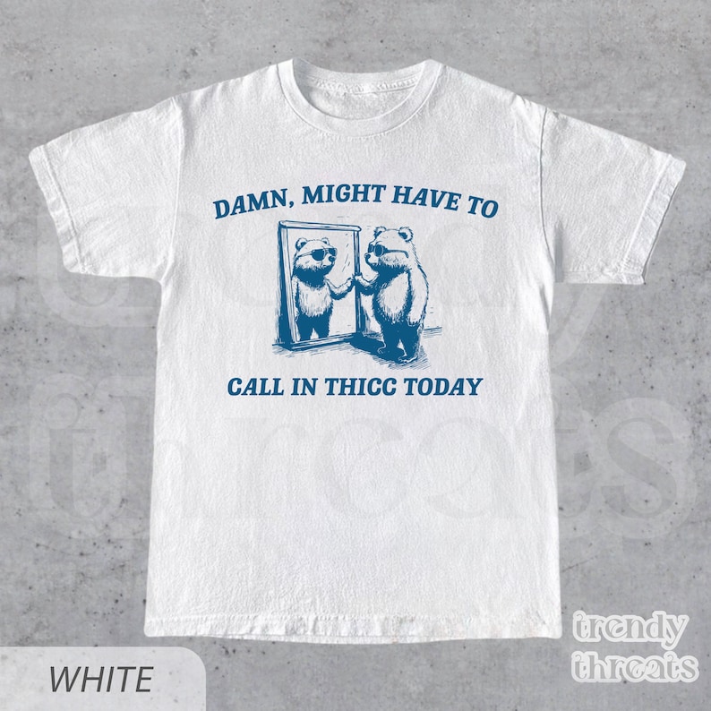 May include: White t-shirt with a blue graphic of two bears looking in a mirror. The text "DAMN, MIGHT HAVE TO CALL IN THICC TODAY" is printed on the shirt.