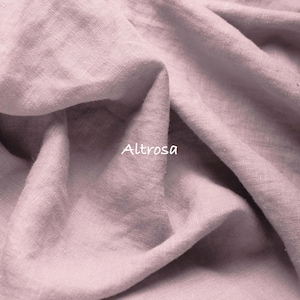 May include: A piece of dusty rose colored fabric with a visible woven texture and folds. The word Altrosa is printed in white text on the surface of the fabric. The material has a matte finish and shows natural creases throughout the textile.