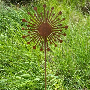 May include: A rusty metal garden stake shaped like a dandelion with a round centre and many thin, pointed petals.