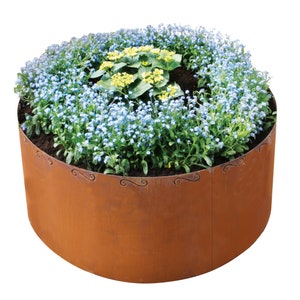 Op de afbeelding: Een cirkelvormige, roestkleurige metalen plantenbak gevuld met blauwe en gele bloemen. De rand van de plantenbak heeft decoratief krulwerk. De bloemen staan in volle bloei en creëren een levendige weergave. De plantenbak is een tuinelement.
