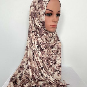 Op de afbeelding: Een beige en bruine hijab met een bloemenprint. De hijab is gemaakt van een zachte, rekbare stof en is perfect voor dagelijks gebruik.