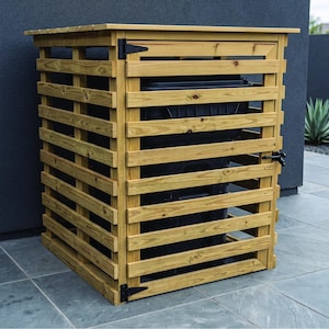 Puede incluir: Un cobertizo de madera para cubos de basura con un diseño de listones horizontales. La estructura cuenta con una puerta frontal abatible con bisagras y pestillo de metal negro, que alberga un gran contenedor de basura de plástico negro.