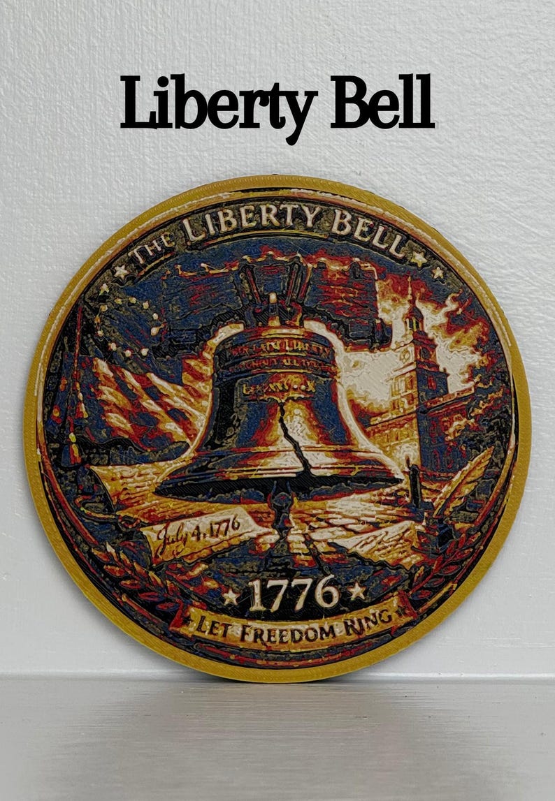 May include: A round, gold-edged emblem featuring the Liberty Bell, an American flag, and Independence Hall. The text "Liberty Bell" is at the top, with "July 4, 1776" and "1776 LET FREEDOM RING" at the bottom. The image is a patriotic design.