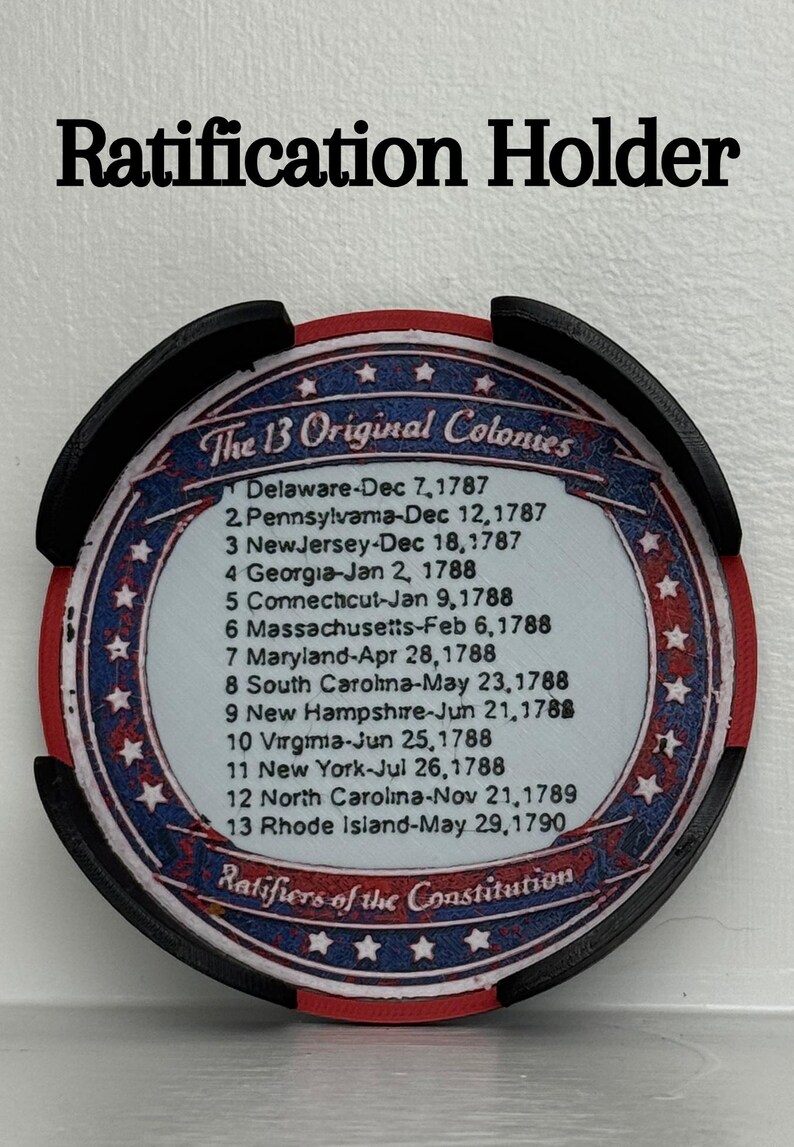 May include: A black and red Ratification Holder with the text "Ratification Holder" at the top. The holder features a circular design with the text "The 13 Original Colonies" and a list of dates.