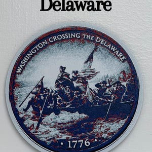 May include: A round, blue, red, and white graphic depicting the historical event, "Crossing the Delaware." The image features a boat with soldiers and the text "Washington Crossing the Delaware" and "1776."