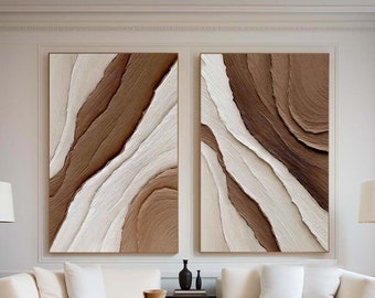 May include: Two abstract paintings with brown and white swirling patterns hang above a white sectional sofa with two throw pillows. A wooden coffee table with a black metal frame sits in front of the sofa. There are three ceramic vases on the coffee table.