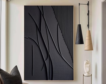 May include: A black and white abstract wall art piece with a textured surface. The art is framed in a thin gold frame and hangs on a white wall.