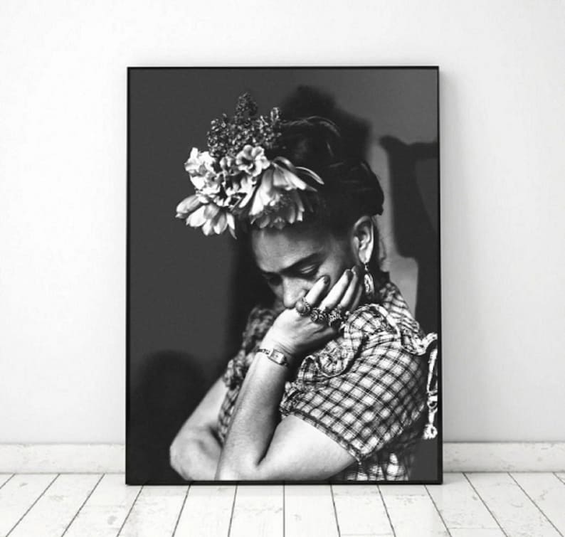 May include: Black and white portrait photograph of a woman with a flower crown on her head. She is wearing a plaid shirt and has her hand on her chin.