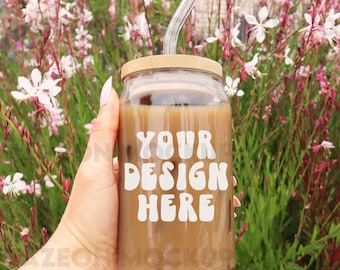 May include: A glass mason jar with a bamboo lid and a glass straw filled with iced coffee. The jar has a white sticker with the text "YOUR DESIGN HERE" in a retro font.